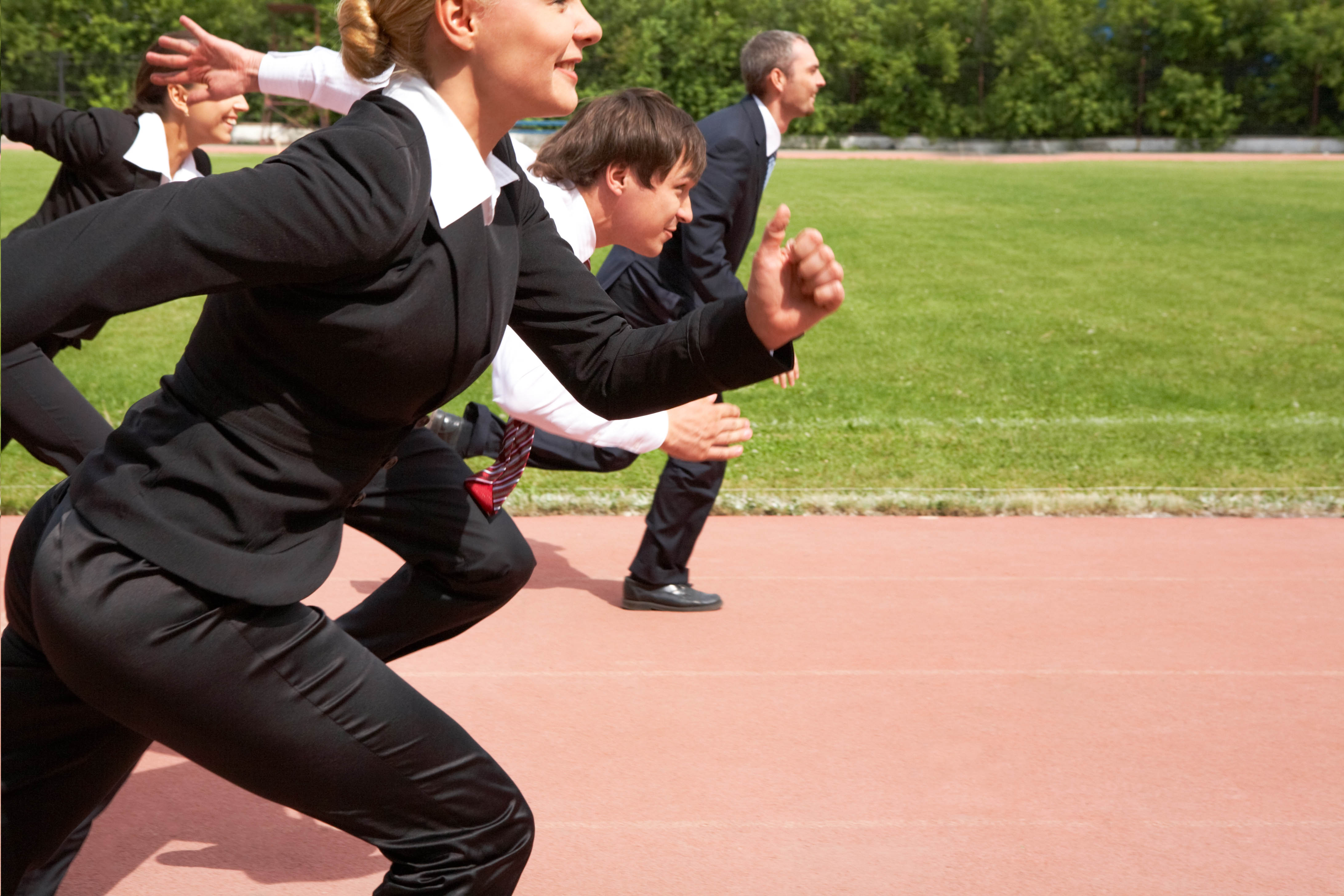 Business people in suits running around a track